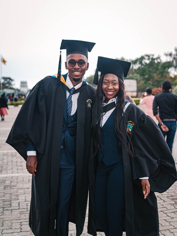 Two graduates in caps and gowns smiling on their graduation day